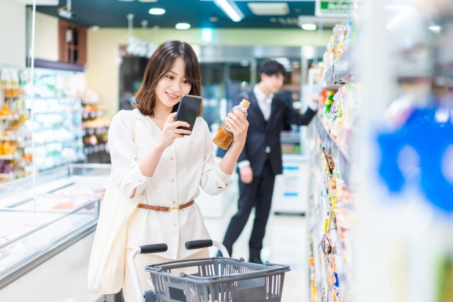 Woman shopping in Japanese grocery store looks at a bottle of salad dressing