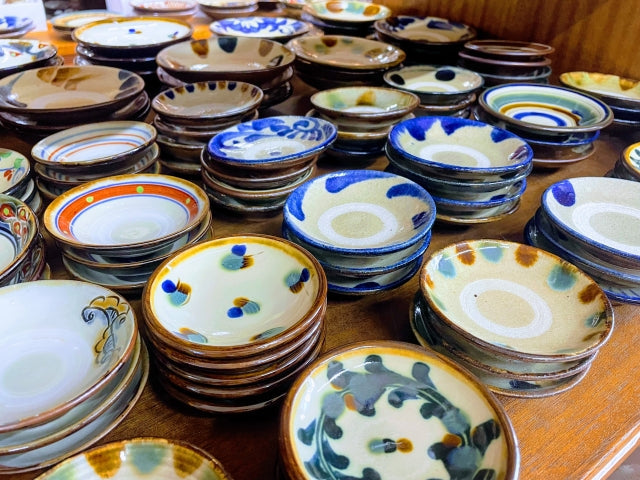 Display of yachimun pottery plates and dishes featuring blue, white, and brown glazes