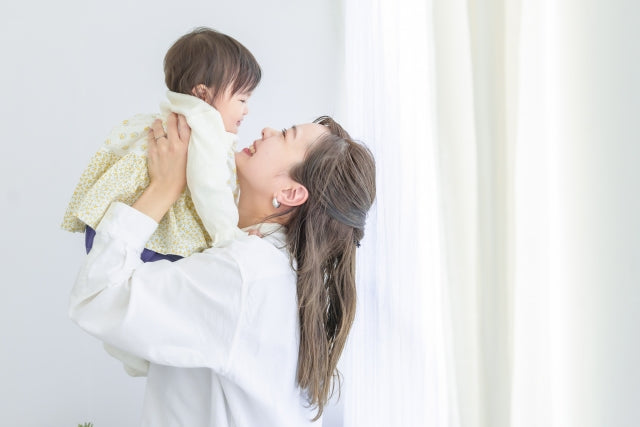 Mother smiling and hold her baby in the air